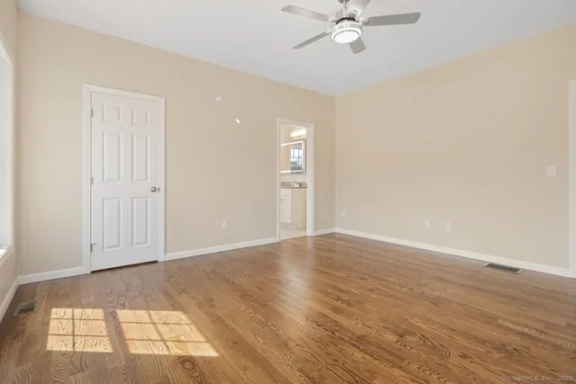 an empty room with wooden floor and windows
