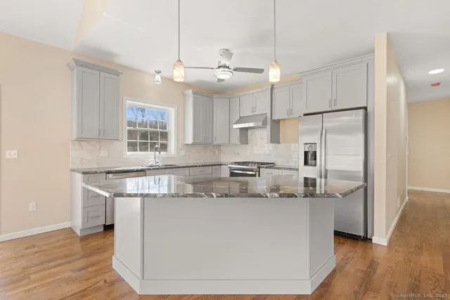 a kitchen with kitchen island stainless steel appliances a sink and a refrigerator