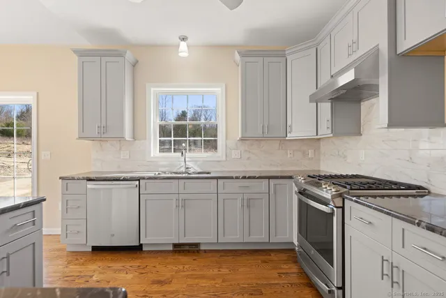 a kitchen with granite countertop a sink stainless steel appliances and cabinets