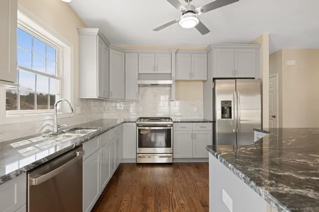 a kitchen with stainless steel appliances granite countertop a sink stove and refrigerator