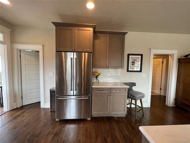 a kitchen with a refrigerator and wooden floor