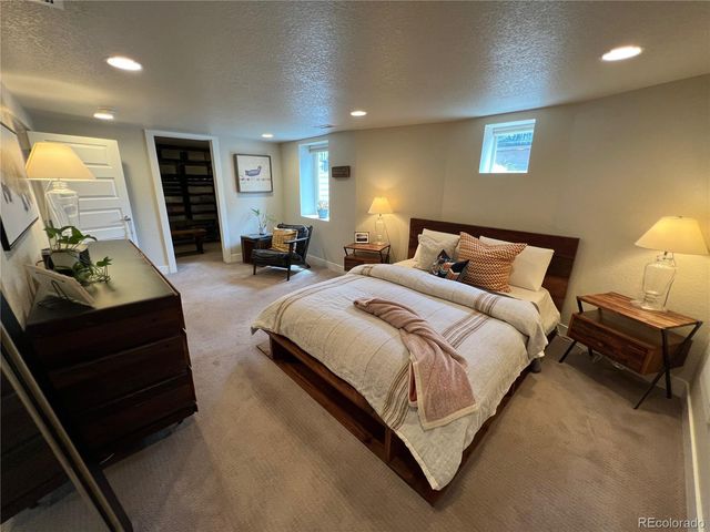a spacious bedroom with a bed a couch and a lamp on table