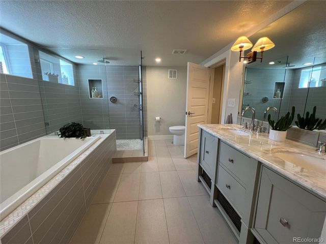 a large bathroom with a large tub a sink a toilet a large mirror and shower
