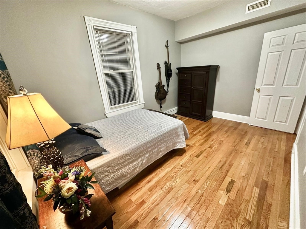 139 Park Street, Unit 4 Chelsea, MA 02150 - Photo 8 of 11 a bedroom with a bed and wooden floor
