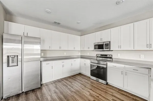 a kitchen with cabinets stainless steel appliances and wooden floor