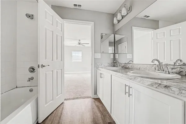 a bathroom with a granite countertop sink a mirror and a bathtub