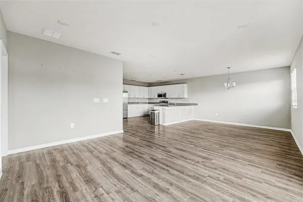 a view of kitchen and empty room with wooden floor