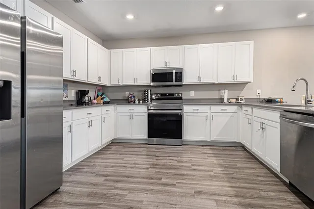 a kitchen with stainless steel appliances granite countertop a stove top oven a sink dishwasher and a refrigerator