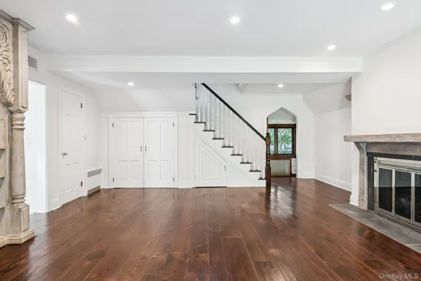 a view of an empty room with wooden floor and a fireplace