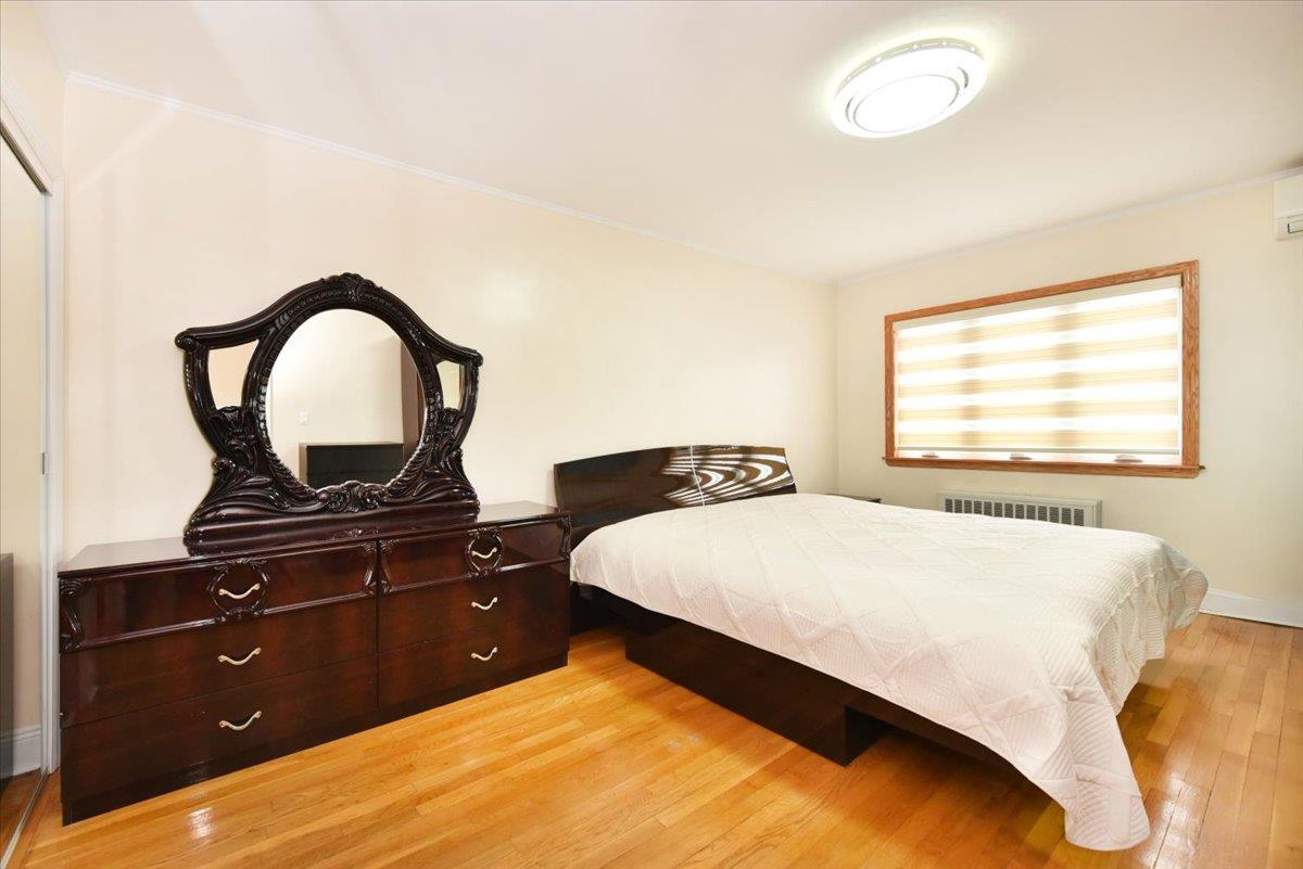 150-15 78th Road Queens, NY 11367 - Photo 15 of 28 Bedroom with a wall mounted air conditioner, baseboards, light wood-style flooring, and radiator heating unit