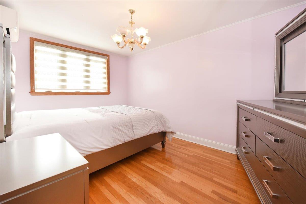 150-15 78th Road Queens, NY 11367 - Photo 17 of 28 Bedroom with baseboards, a chandelier, crown molding, and light wood finished floors