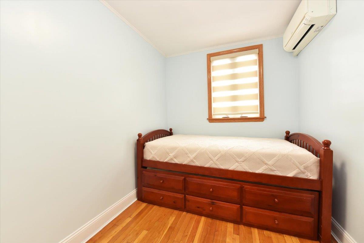 150-15 78th Road Queens, NY 11367 - Photo 20 of 28 Bedroom with light wood-style flooring, an AC wall unit, crown molding, and baseboards