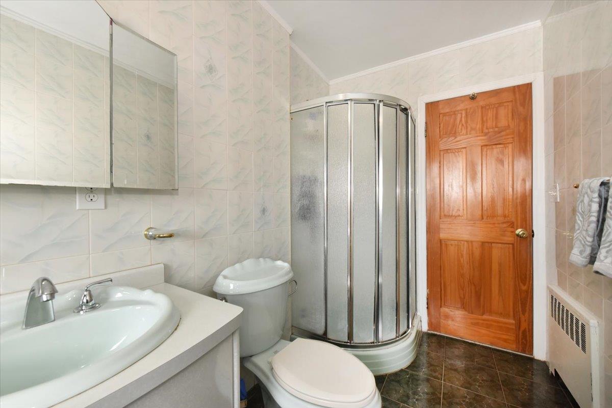150-15 78th Road Queens, NY 11367 - Photo 21 of 28 Bathroom with radiator, tile walls, crown molding, and a stall shower
