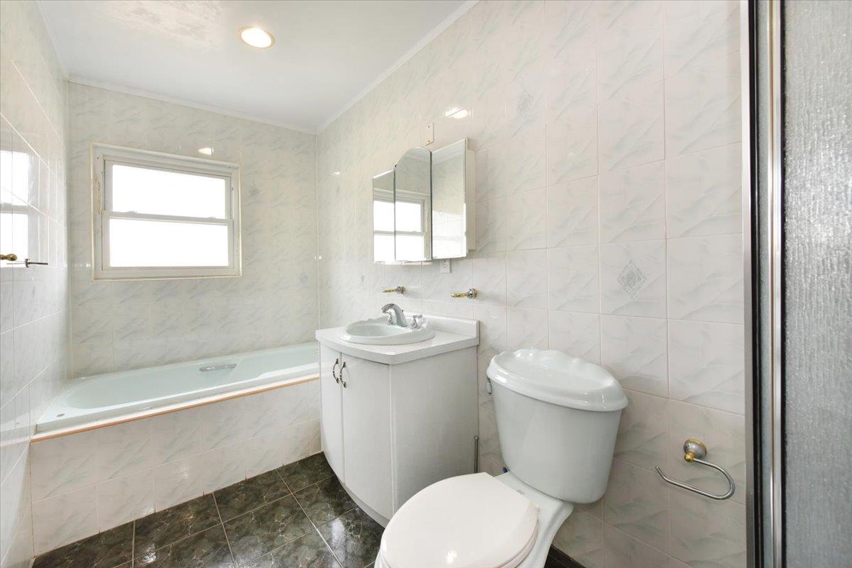 150-15 78th Road Queens, NY 11367 - Photo 22 of 28 Bathroom with tiled tub, toilet, tile walls, and vanity