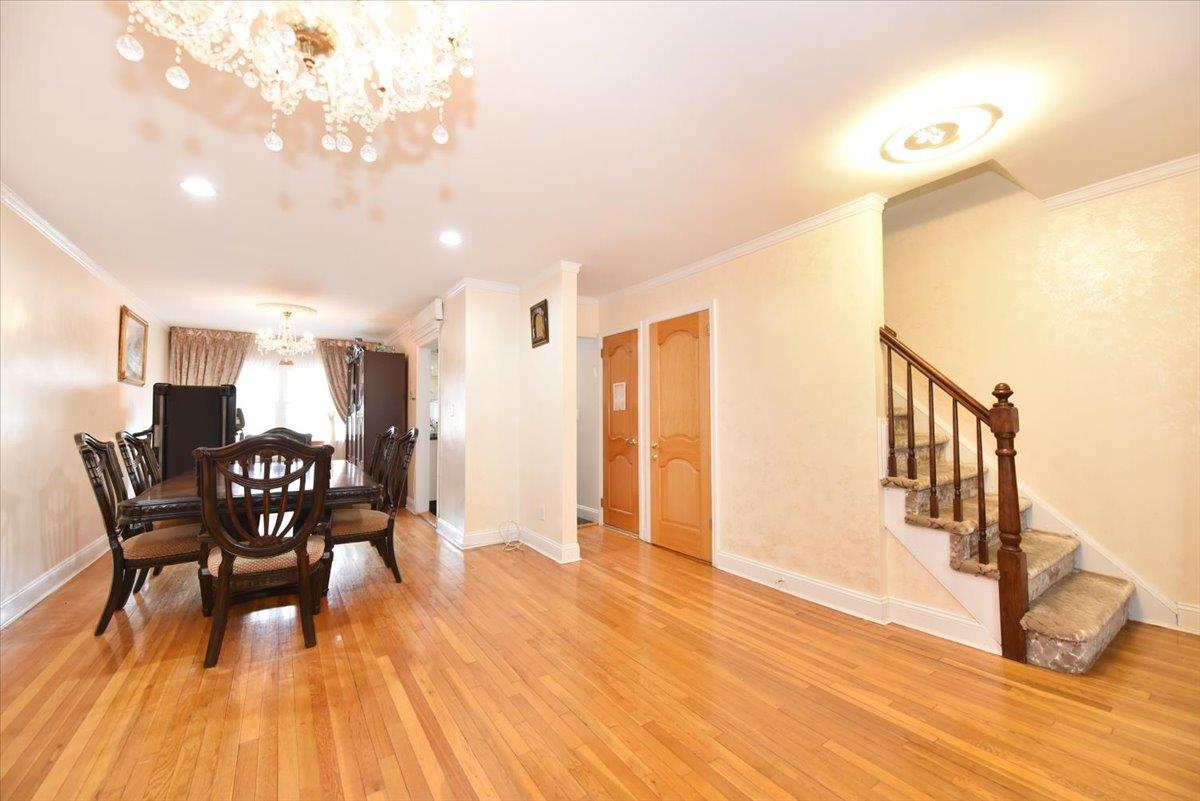150-15 78th Road Queens, NY 11367 - Photo 5 of 28 Dining room with baseboards, an inviting chandelier, light wood-style flooring, stairs, and crown molding