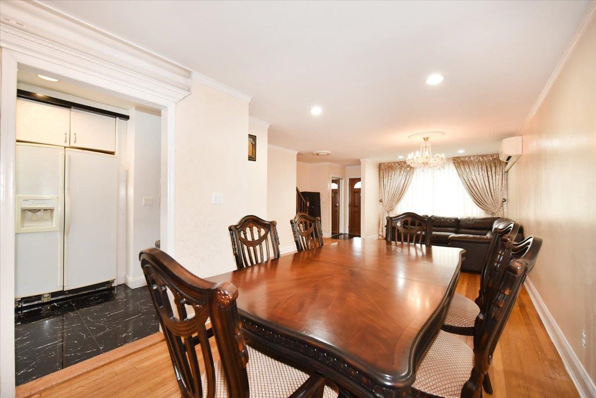 150-15 78th Road Queens, NY 11367 - Photo 7 of 28 Dining space with ornamental molding, a wall mounted AC, wood finished floors, an inviting chandelier, and baseboards