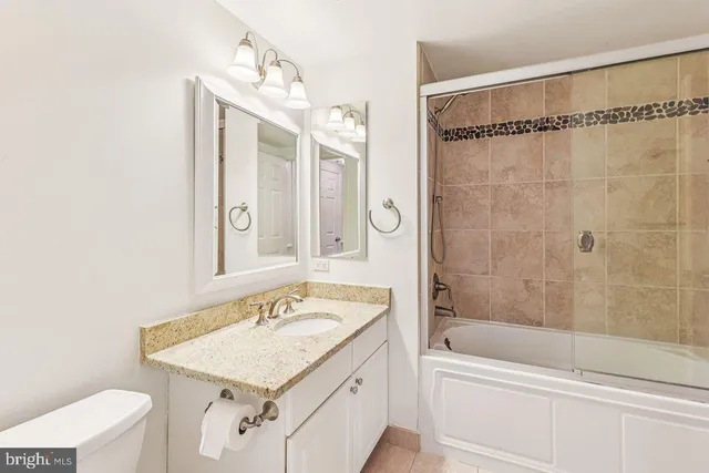 a bathroom with a granite countertop sink a toilet and shower
