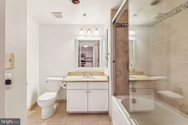 a bathroom with a granite countertop toilet a sink and a bathtub
