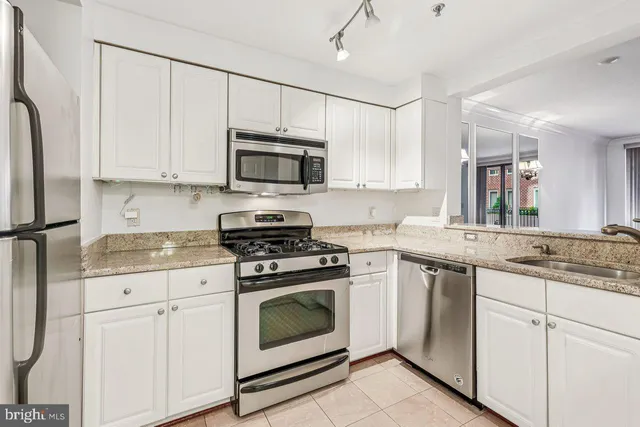 a kitchen with granite countertop white cabinets sink and stainless steel appliances