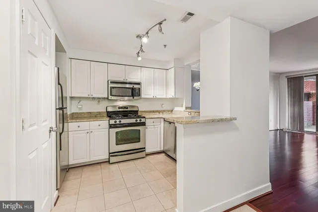 a kitchen with cabinets stainless steel appliances and a counter space