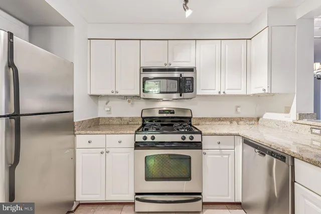 a kitchen with cabinets stainless steel appliances and wooden floor