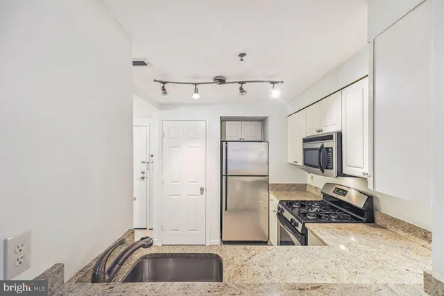 a kitchen with stainless steel appliances granite countertop a refrigerator a stove and a sink