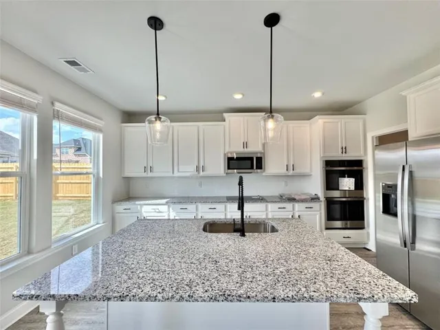 a kitchen with kitchen island granite countertop a counter space cabinets and appliances