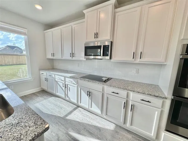 a kitchen with stainless steel appliances granite countertop a stove a sink and a microwave