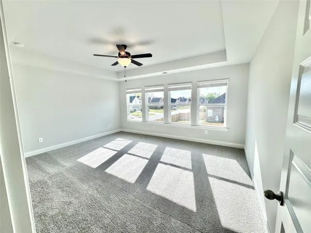 an empty room with windows and ceiling fan