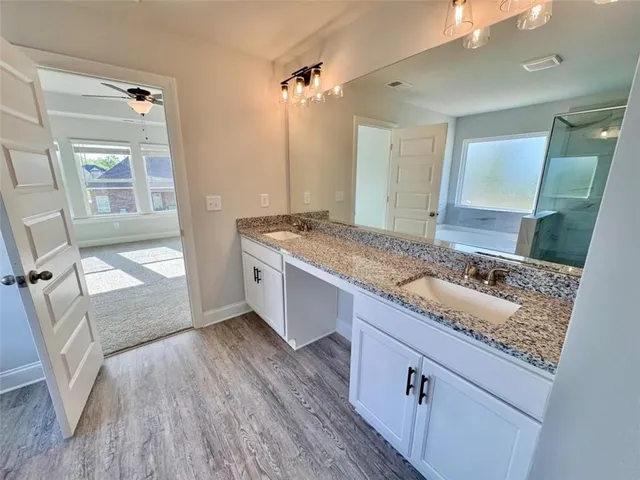 a bathroom with a granite countertop sink a mirror and shower