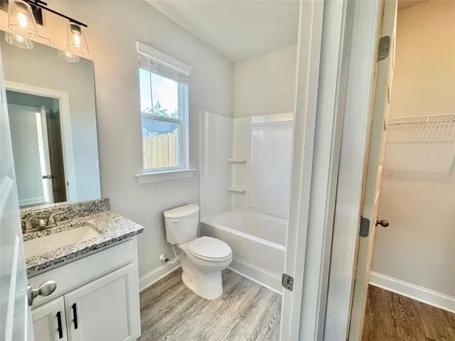 a bathroom with a granite countertop toilet a sink and a mirror
