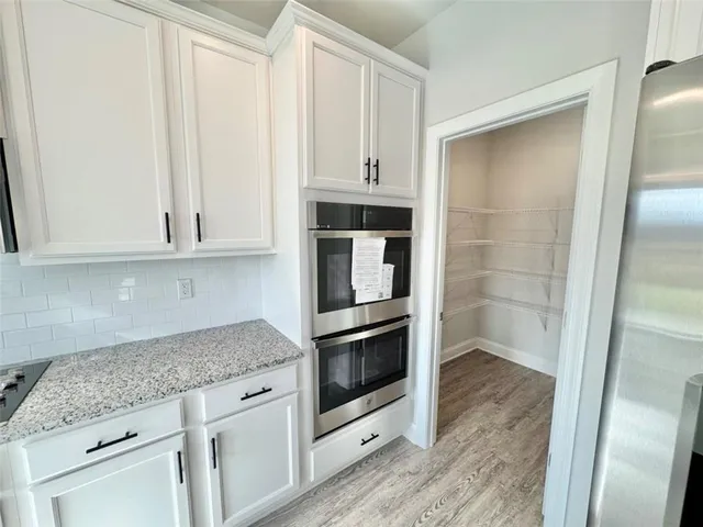 a kitchen with granite countertop white cabinets and stainless steel appliances