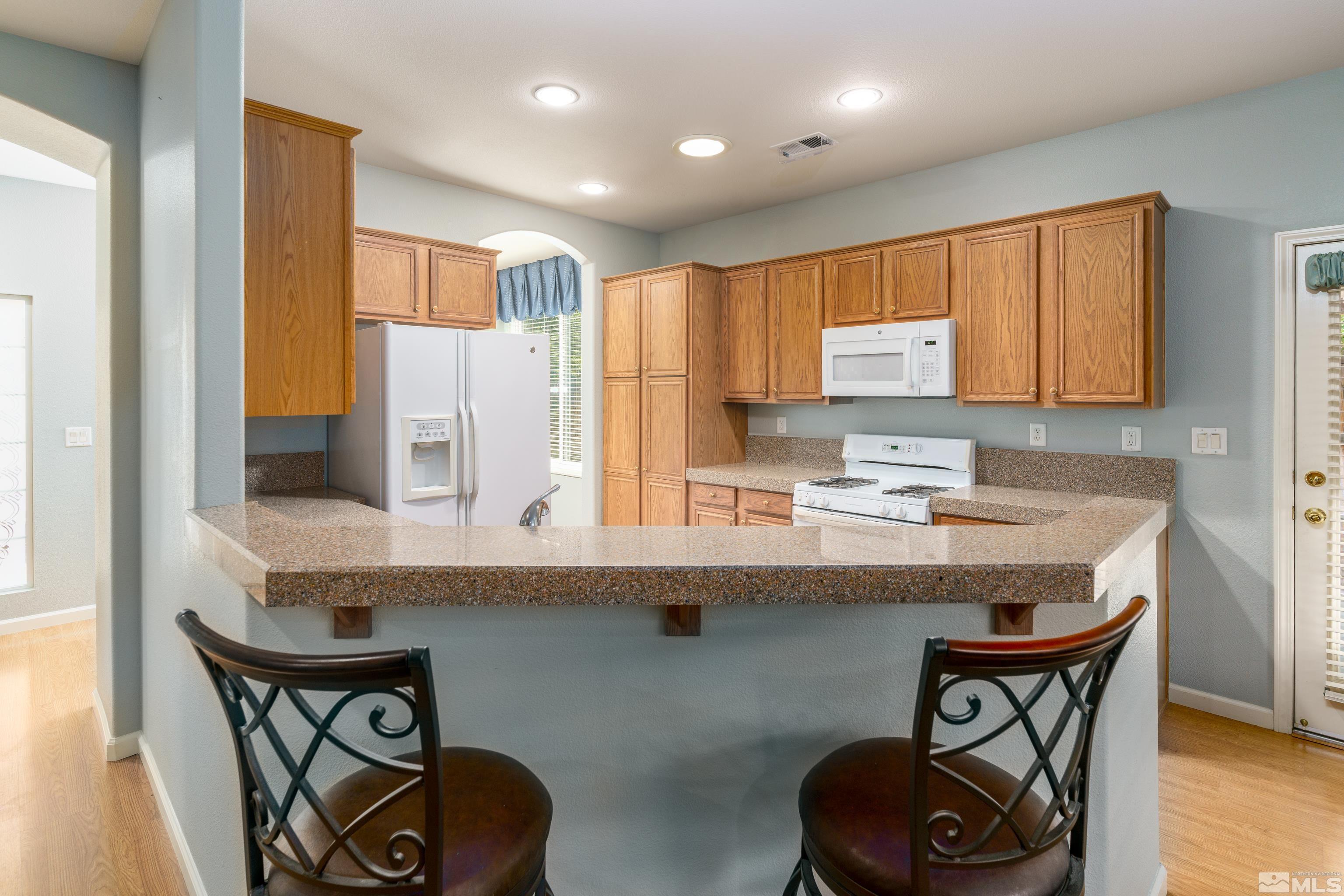 10412 Rockport Lane Reno, NV 89521 - Photo 5 of 15 a kitchen with stainless steel appliances granite countertop a table chairs in it and wooden floors
