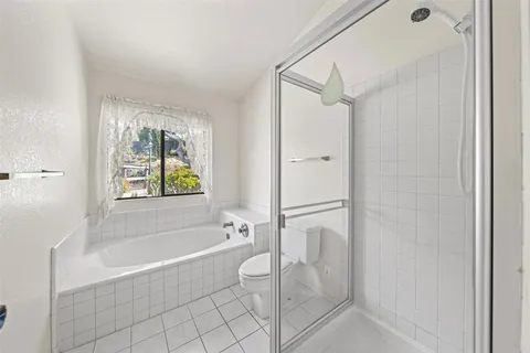 a bathroom with a granite countertop bathtub shower and toilet