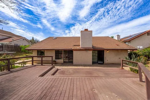 a view of a house with wooden deck and furniture