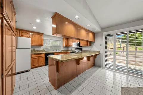 a kitchen with stainless steel appliances granite countertop a stove a sink and a refrigerator