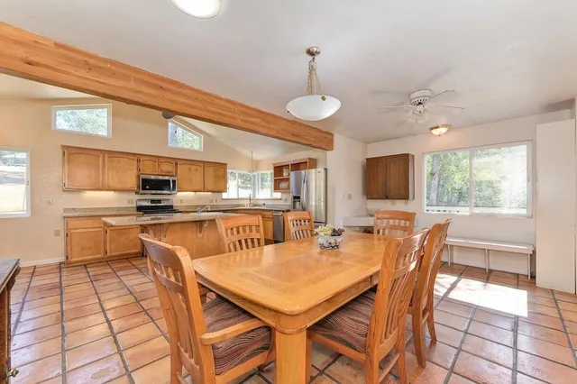a kitchen with stainless steel appliances kitchen island granite countertop a table chairs and a refrigerator