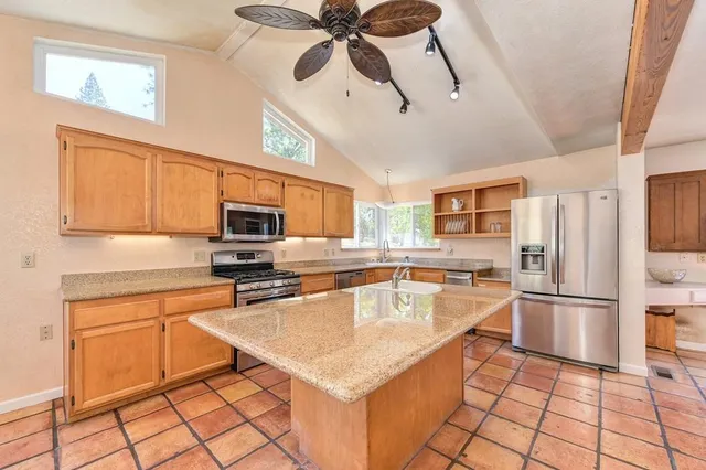 a kitchen with stainless steel appliances granite countertop a refrigerator a oven a sink a stove and white cabinets with wooden floor