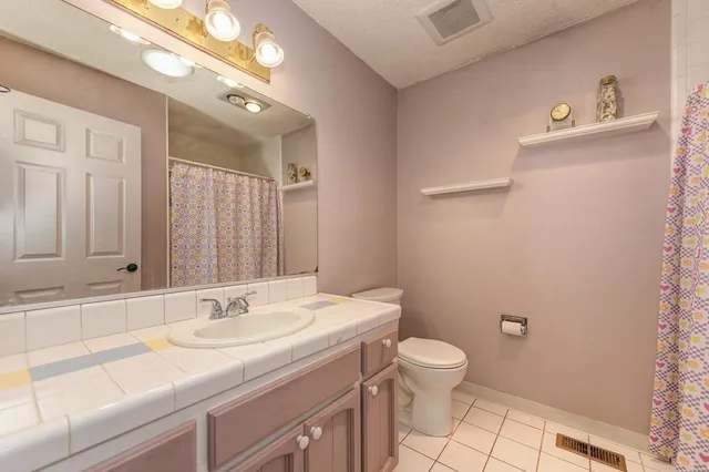 a bathroom with a granite countertop sink a toilet and a mirror