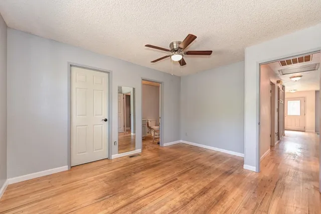 a view of empty room with wooden floor and fan
