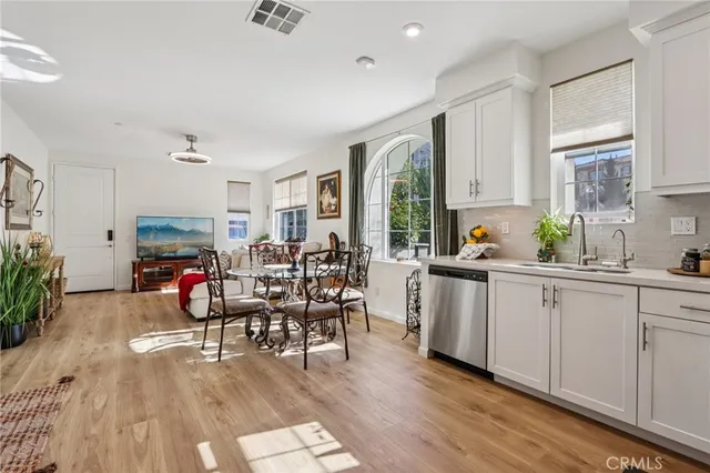 a kitchen with stainless steel appliances granite countertop a stove top oven a sink a dining table and chairs with wooden floor