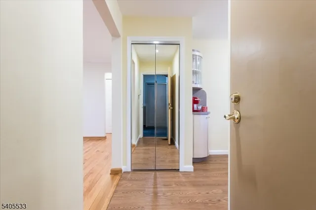 a view of a hallway with wooden floor and a bathroom