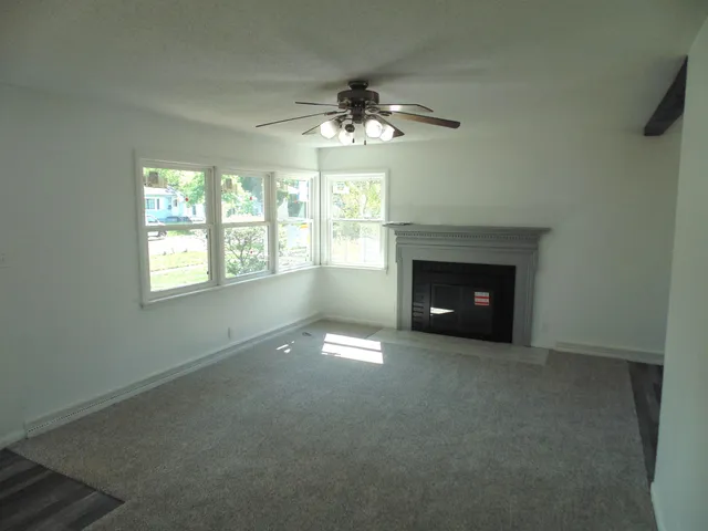 an empty room with windows and fireplace