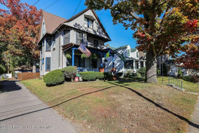 a view of a white house next to a road and yard