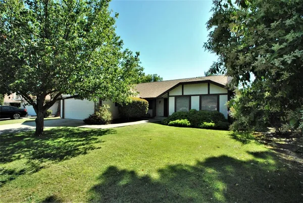 a front view of a house with yard and tree