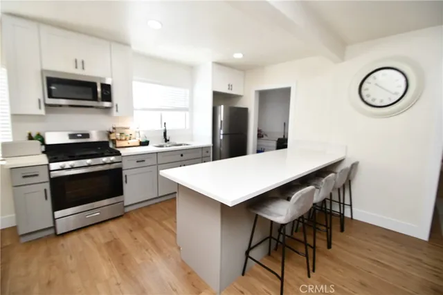 a kitchen with stainless steel appliances kitchen island a table chairs microwave and sink