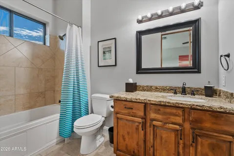 a bathroom with a granite countertop toilet sink and mirror