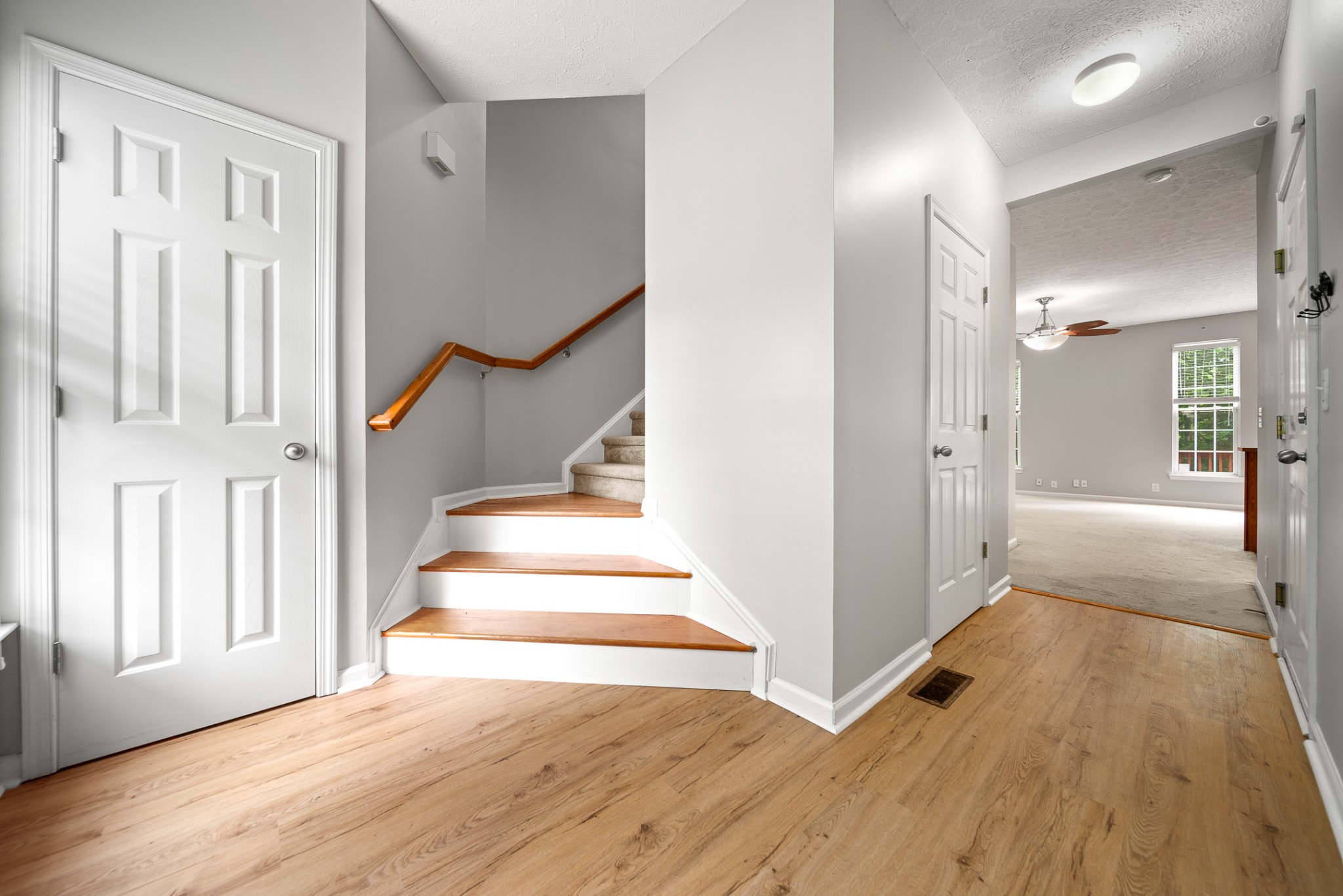 a view of a hallway with wooden floor and staircase