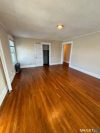 a view of an empty room with wooden floor and a window