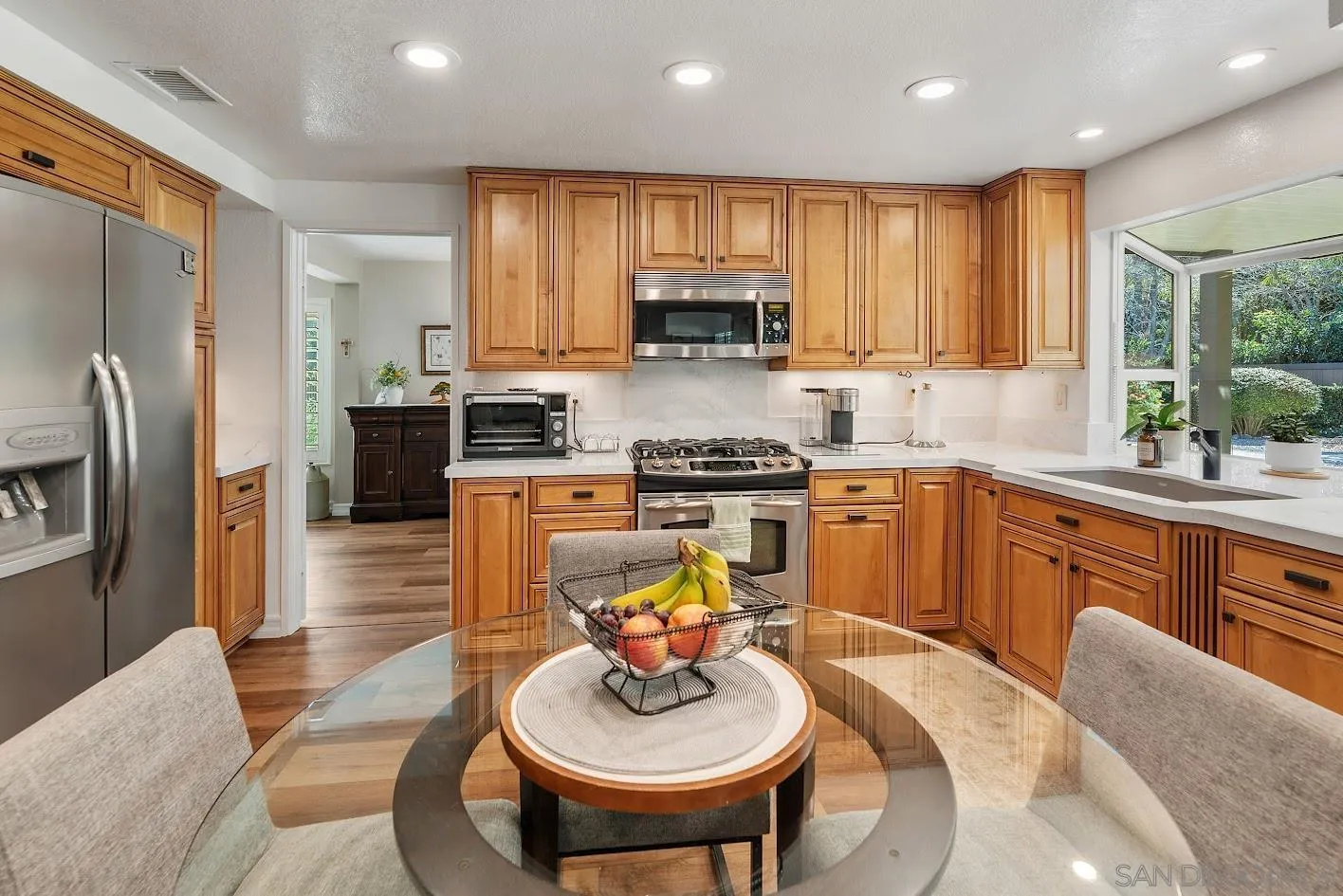14922 Derringer Road Poway, CA 92064 - Photo 4 of 66 a kitchen with stainless steel appliances granite countertop a sink a stove a refrigerator cabinets and a dining table with wooden floor